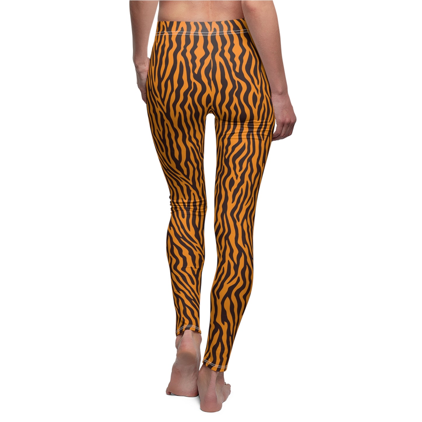 A person shown from the back wearing high-waisted leggings with a bold orange and black wavy tiger-stripe pattern, standing barefoot against a plain white background. Bold Orange Leggings with Wild Animal Pattern
