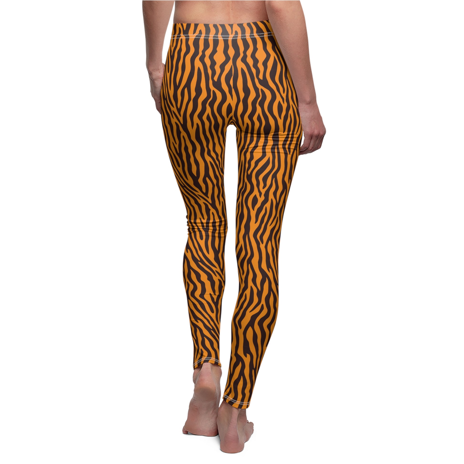 A person shown from the back wearing high-waisted leggings with a bold orange and black wavy tiger-stripe pattern, standing barefoot against a plain white background. Bold Orange Leggings with Wild Animal Pattern