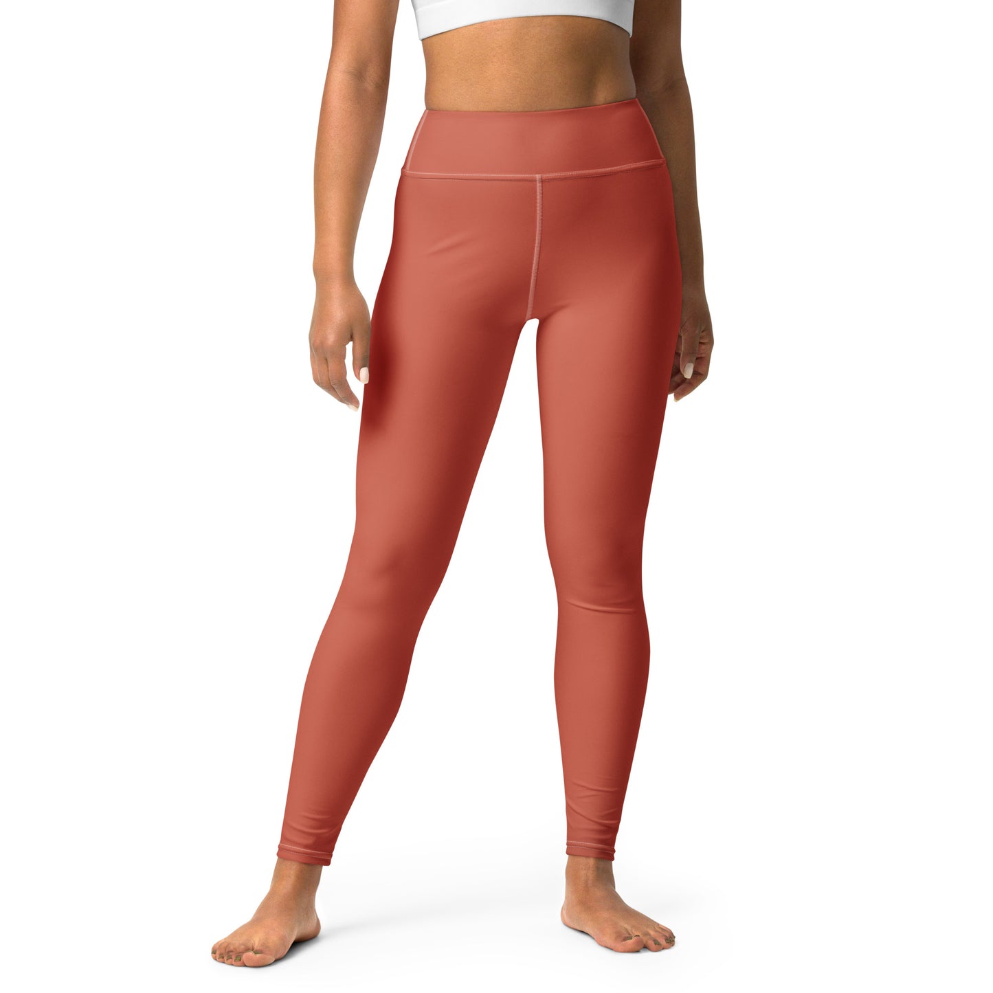 A model wearing high-waisted, full-length leggings in a muted terracotta or rust color, shown from the waist down against a plain white background. Bold Stretchy Yoga Leggings with Solid Dark Coral