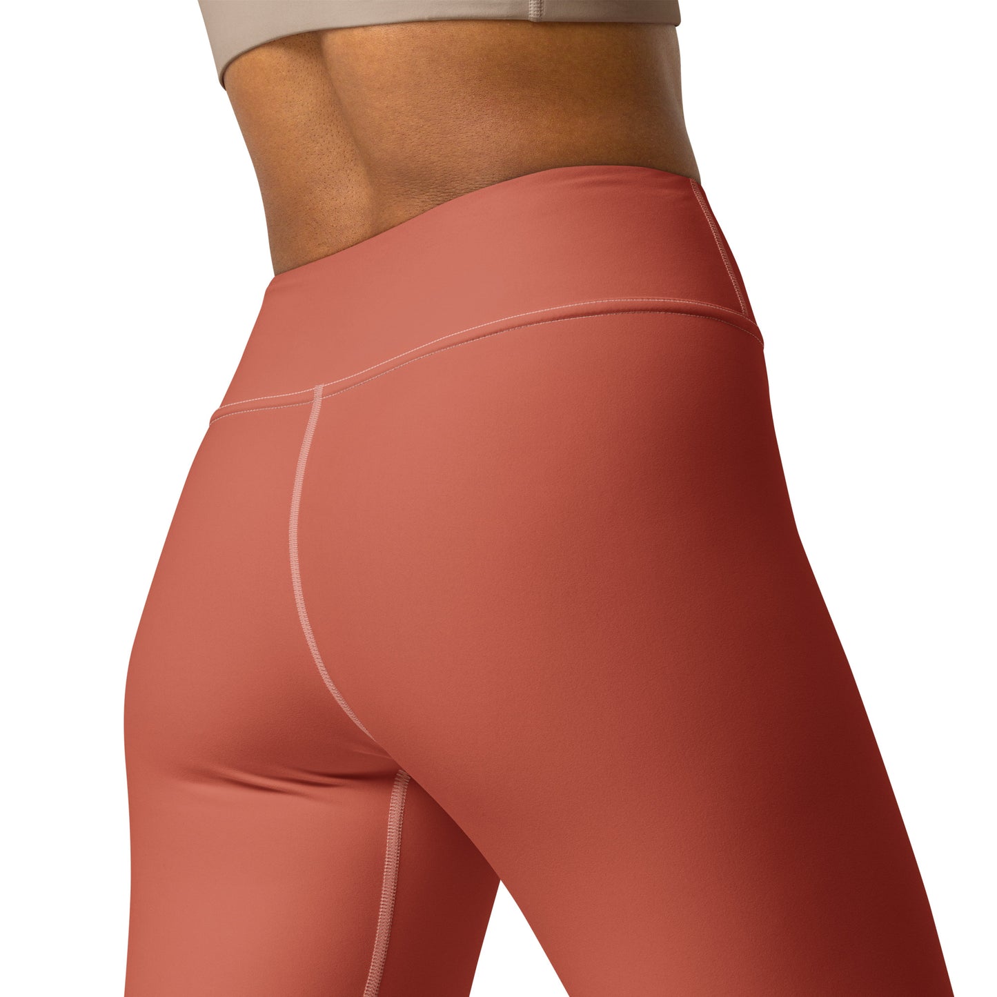 Close-up of a model wearing high-waisted athletic leggings in a muted terracotta or rust color, showing the waistband, hip seam, and thigh contour against a plain white background. Bold Stretchy Yoga Leggings with Solid Dark Coral Elegant