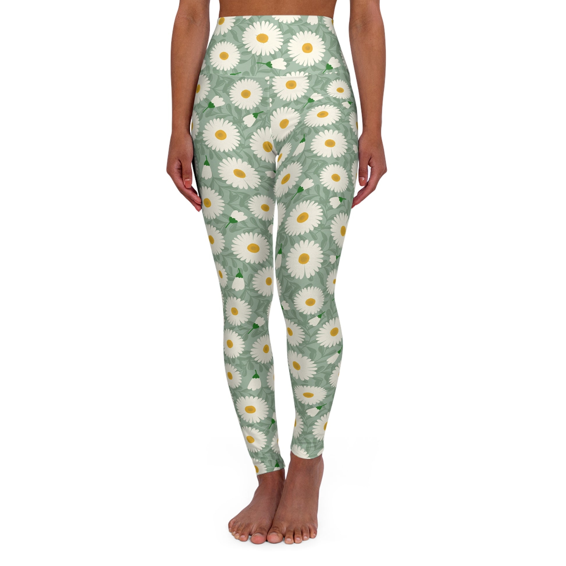 A model is shown from the waist down wearing high-waisted leggings with a green background and a white and yellow daisy floral pattern, standing barefoot against a white background.