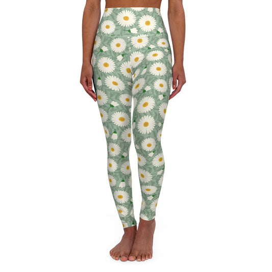 A model is shown from the waist down wearing high-waisted leggings with a green background and a white and yellow daisy floral pattern, standing barefoot against a white background.
