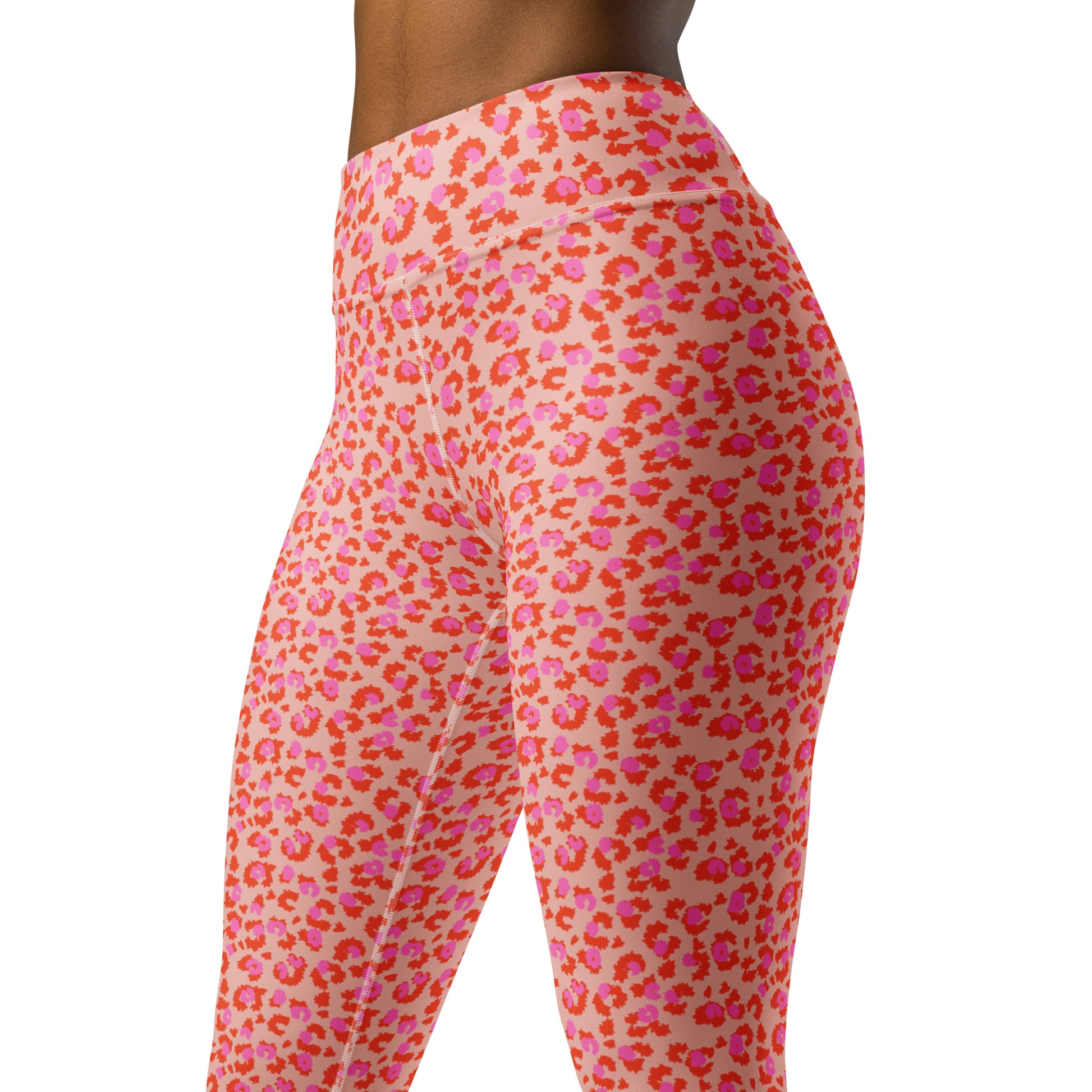 Close-up side view of a person wearing high-waisted leggings with an allover leopard-style print in pink, coral, and orange on a light peach base, against a plain white background. Chic Pink Leopard Print Yoga Pants for Workouts Activewear