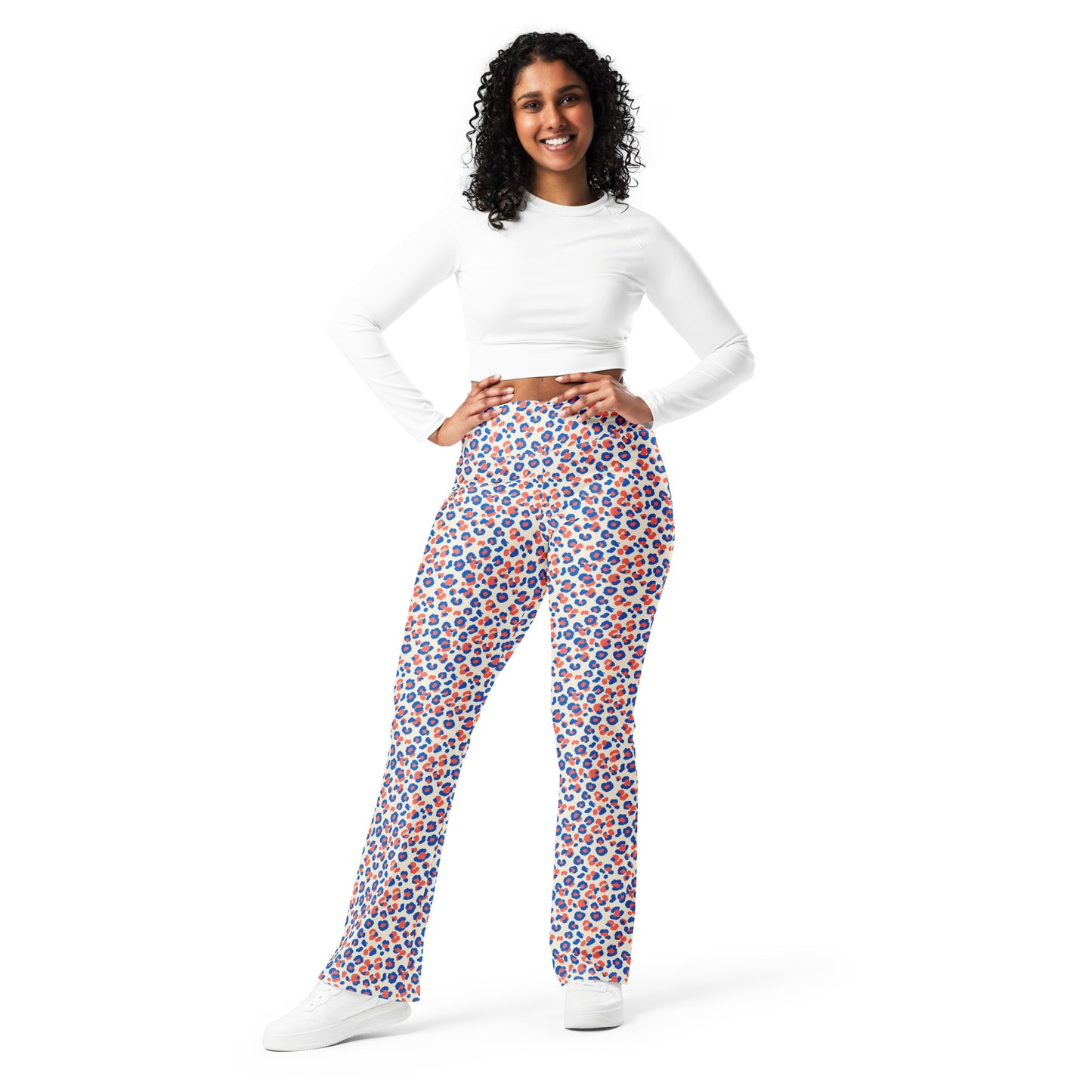 A woman modeling high-waisted, wide-leg pants with a vibrant blue, orange, and white geometric pattern, paired with a white long-sleeve crop top and white sneakers, against a solid white background. Colorful Leopard Print Flare Leggings Active Wear