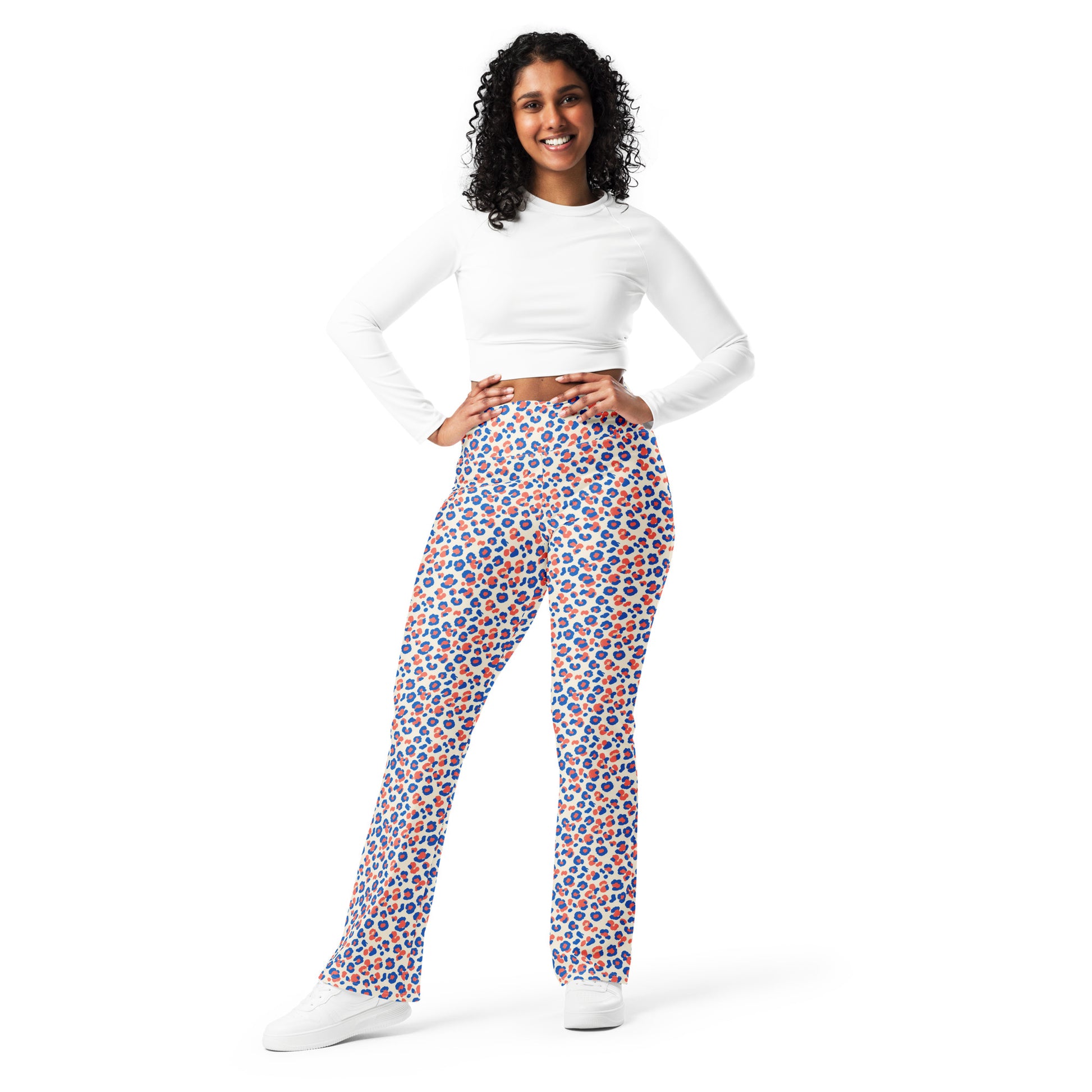 A woman modeling high-waisted, wide-leg pants with a vibrant blue, orange, and white geometric pattern, paired with a white long-sleeve crop top and white sneakers, against a solid white background. Colorful Leopard Print Flare Leggings Active Wear
