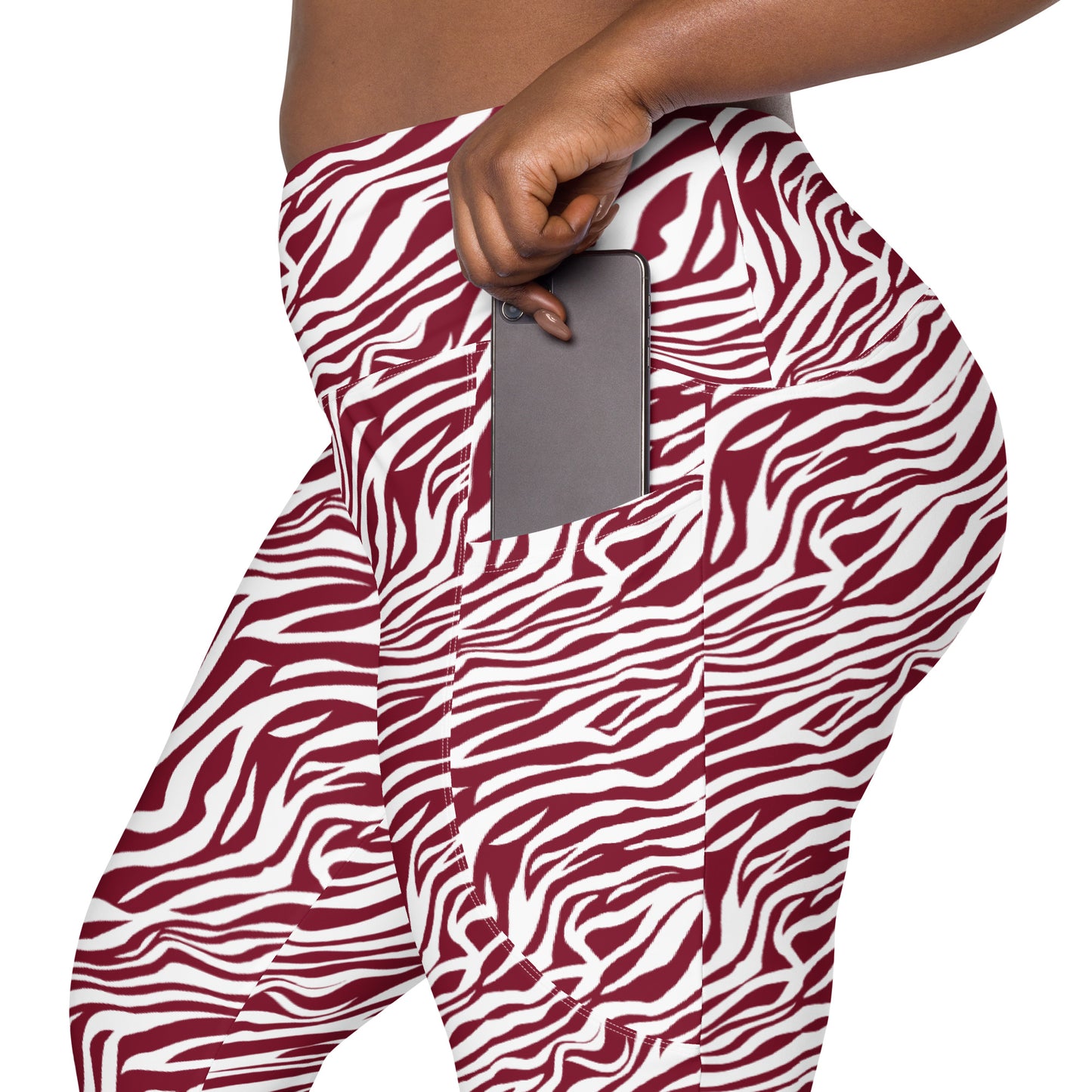 A close-up of a person wearing high-waisted leggings with a bold red and white zebra print. The person is shown from the waist down, holding a gray smartphone in a side pocket of the leggings. Comfortable Bold Red Zebra Print Leggings with Pockets Activewear