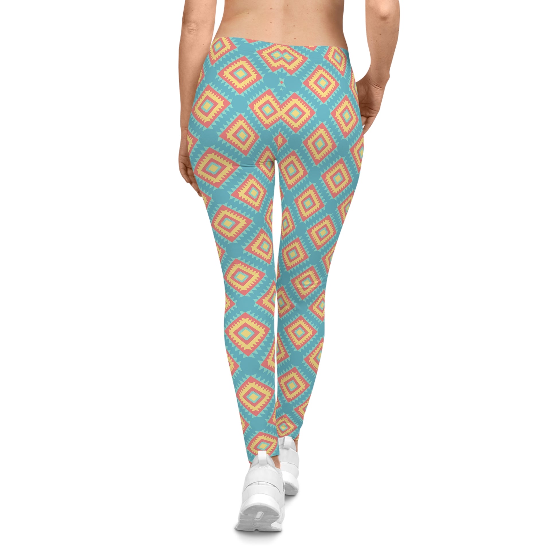 A person shown from the back wearing high-waisted leggings with a repeating geometric diamond pattern in turquoise, peach, and cream, paired with white sneakers on a plain white background.