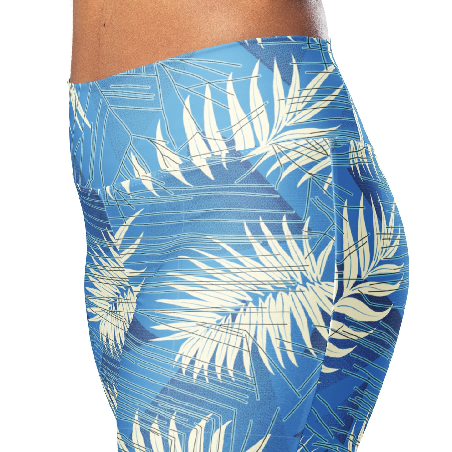 Close-up side view of a person wearing high-waisted leggings with a blue tropical palm leaf print on a white background. Contemporary Tropical Palm Leaves Flare Leggings Activewear
