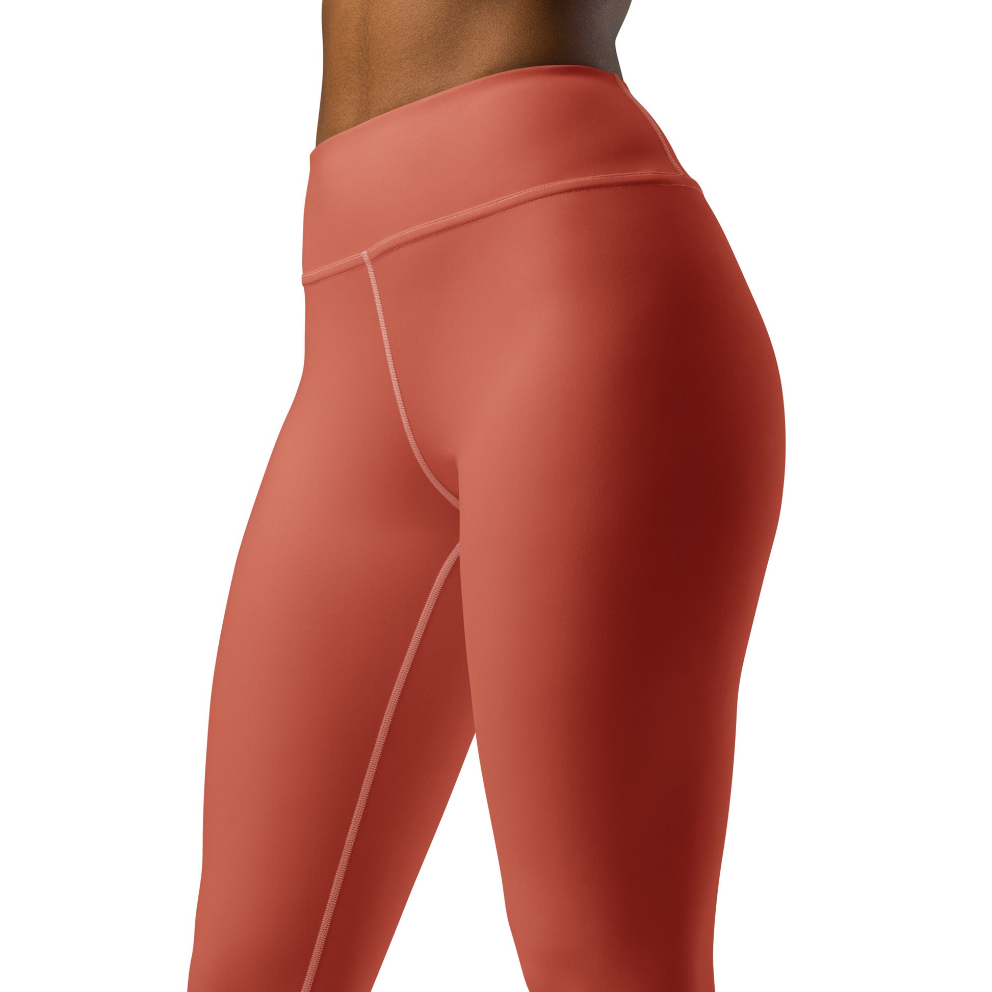 Close-up side view of a person wearing high-waisted athletic leggings in a muted terracotta or burnt orange color, with thin contrasting light piping details on a plain white background. Cute Bold Stretchy Yoga Leggings with Solid Dark Coral