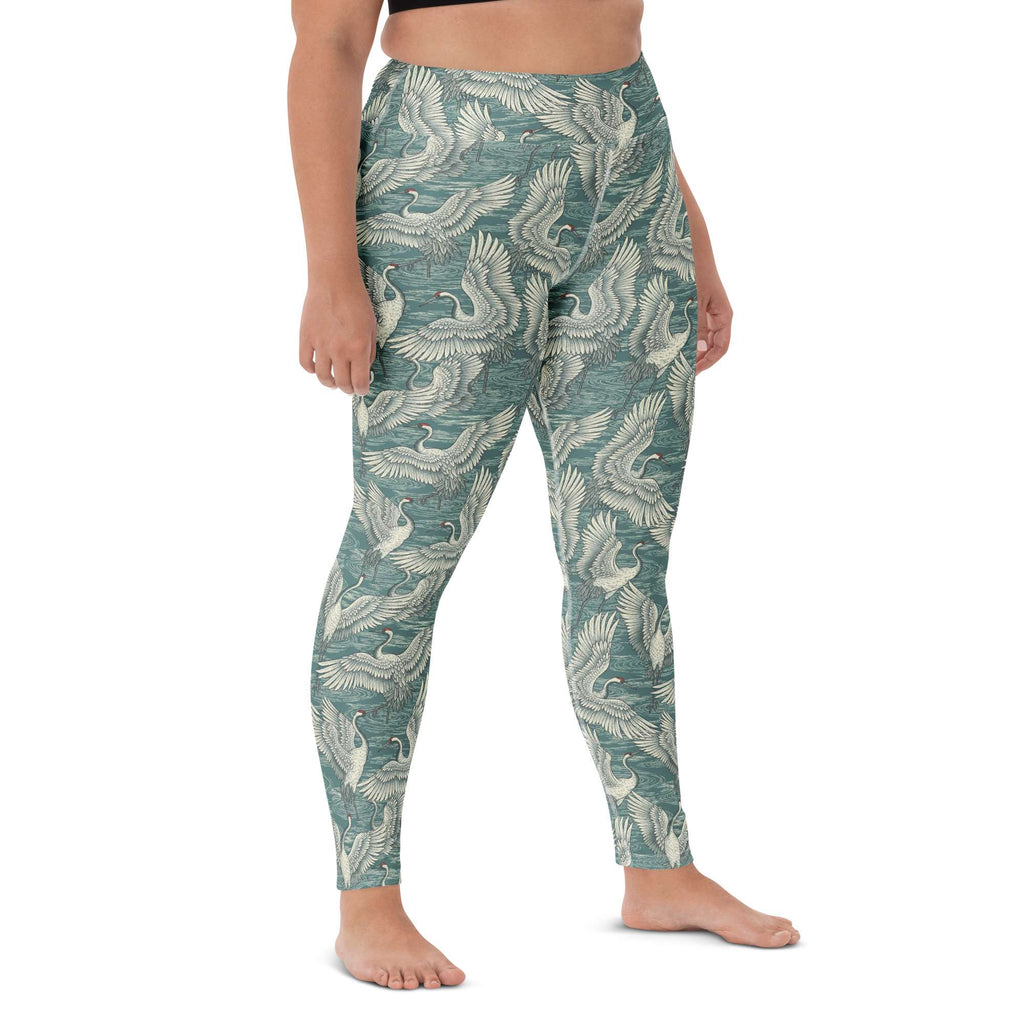 A person modeling high-waisted leggings with an all-over teal and off-white crane pattern, shown from the waist down against a plain white studio background. Cute Minimalist Bold Yoga Leggings in Artistic Crane Dance Print