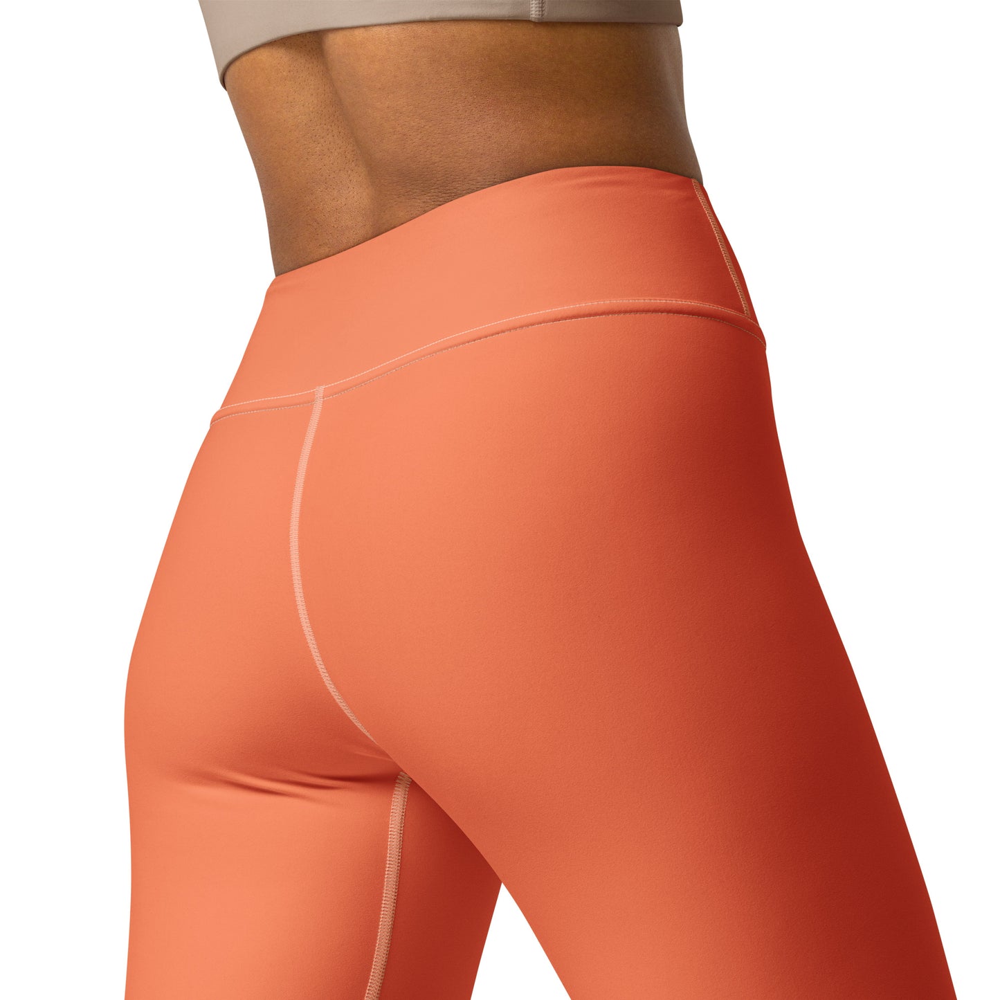 Close-up of a model wearing high-waisted athletic leggings in a solid coral-orange color, showing the side and back fit against a plain white background. Elegant Chic Comfortable Yoga Pants in Solid Coral Shade for Activewear