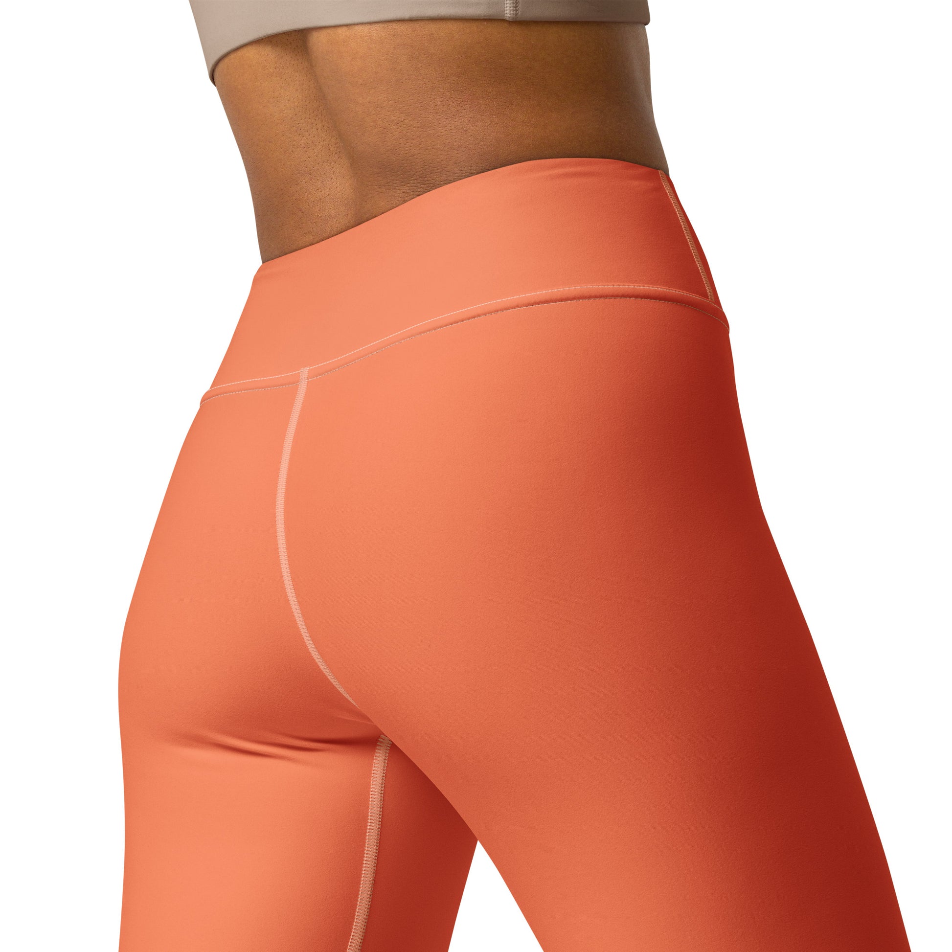 Close-up of a model wearing high-waisted athletic leggings in a solid coral-orange color, showing the side and back fit against a plain white background. Elegant Chic Comfortable Yoga Pants in Solid Coral Shade for Activewear