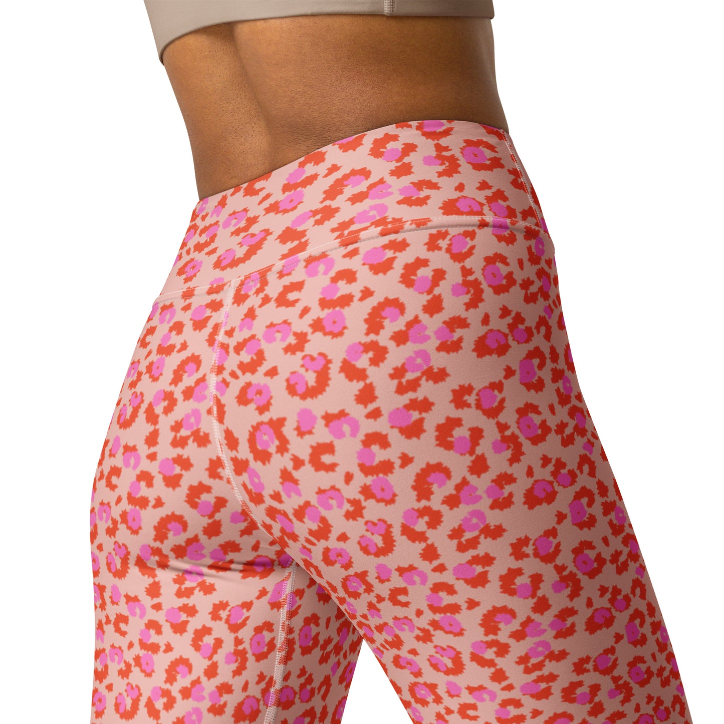 Close-up of a model wearing high-waisted leggings with a pink, orange, and red abstract floral pattern on a light peach background, shown from a side-rear angle against a white studio background. Elegant Chic Pink Leopard Print Yoga Pants for Workouts Activewear