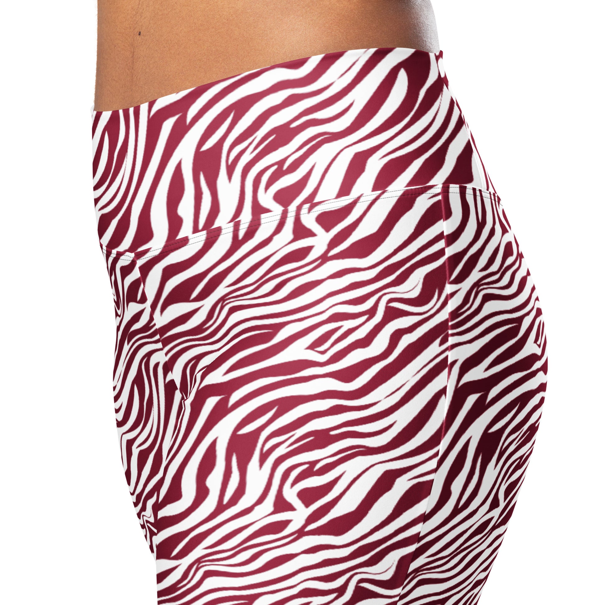 A close-up side view of a person wearing leggings with a bold wavy zebra-like pattern in burgundy red and white against a plain white background. Elegant Comfortable Bold Red Zebra Print Flare Leggings