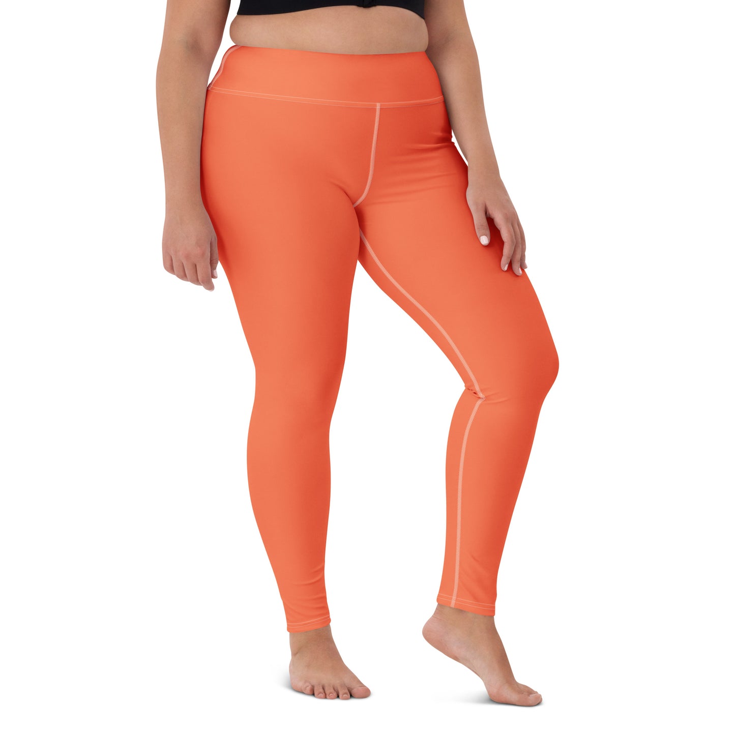 A model wearing bright orange high-waisted athletic leggings with thin white contrast stitching, shown from the waist down on a white background. Fashionable Chic Comfortable Yoga Pants in Solid Coral Shade for Activewear