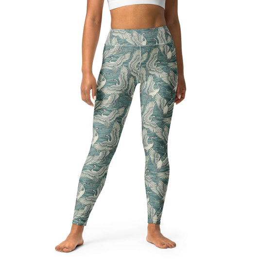 A model wearing high-waisted leggings with an all-over teal and off-white crane pattern, shown from the waist down on a plain white studio background. Minimalist Bold Yoga Leggings in Artistic Crane Dance Print