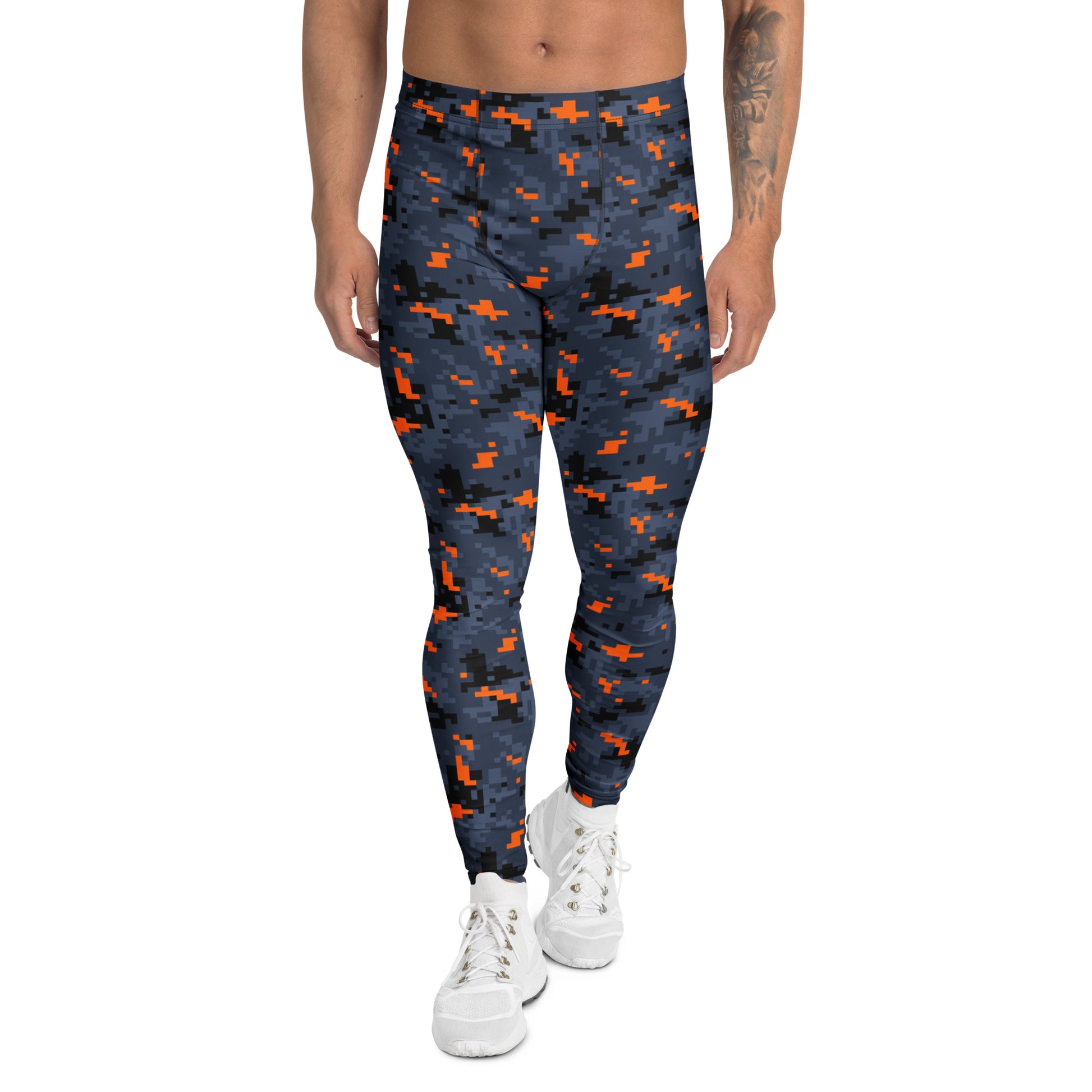 A person modeling high-waisted leggings with a dark navy blue and black pixelated camouflage pattern accented by bright orange shapes, paired with white sneakers against a plain white background.