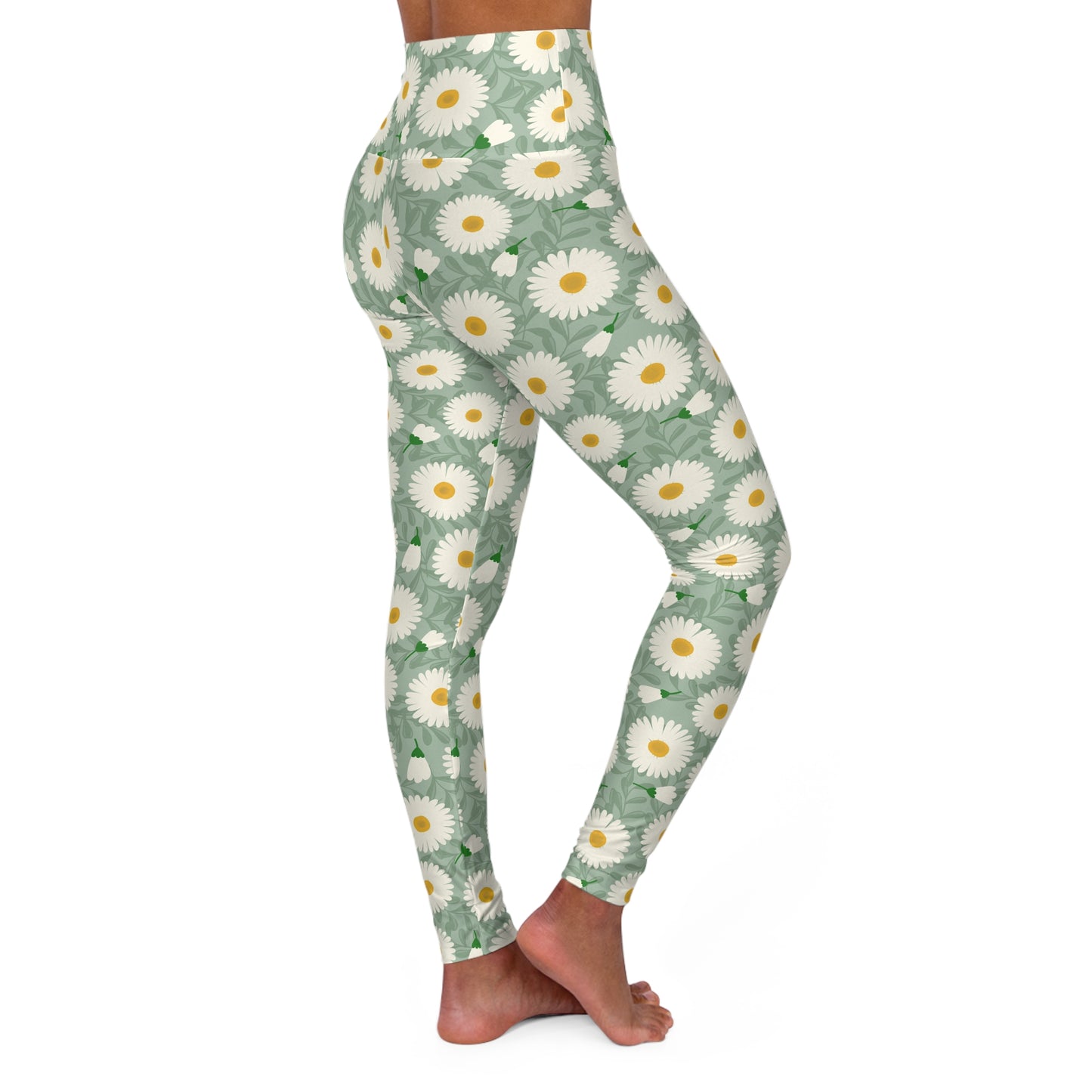 A person modeling high-waisted leggings with a repeating daisy floral print on a light sage green background, shown from the waist down against a plain white studio background.