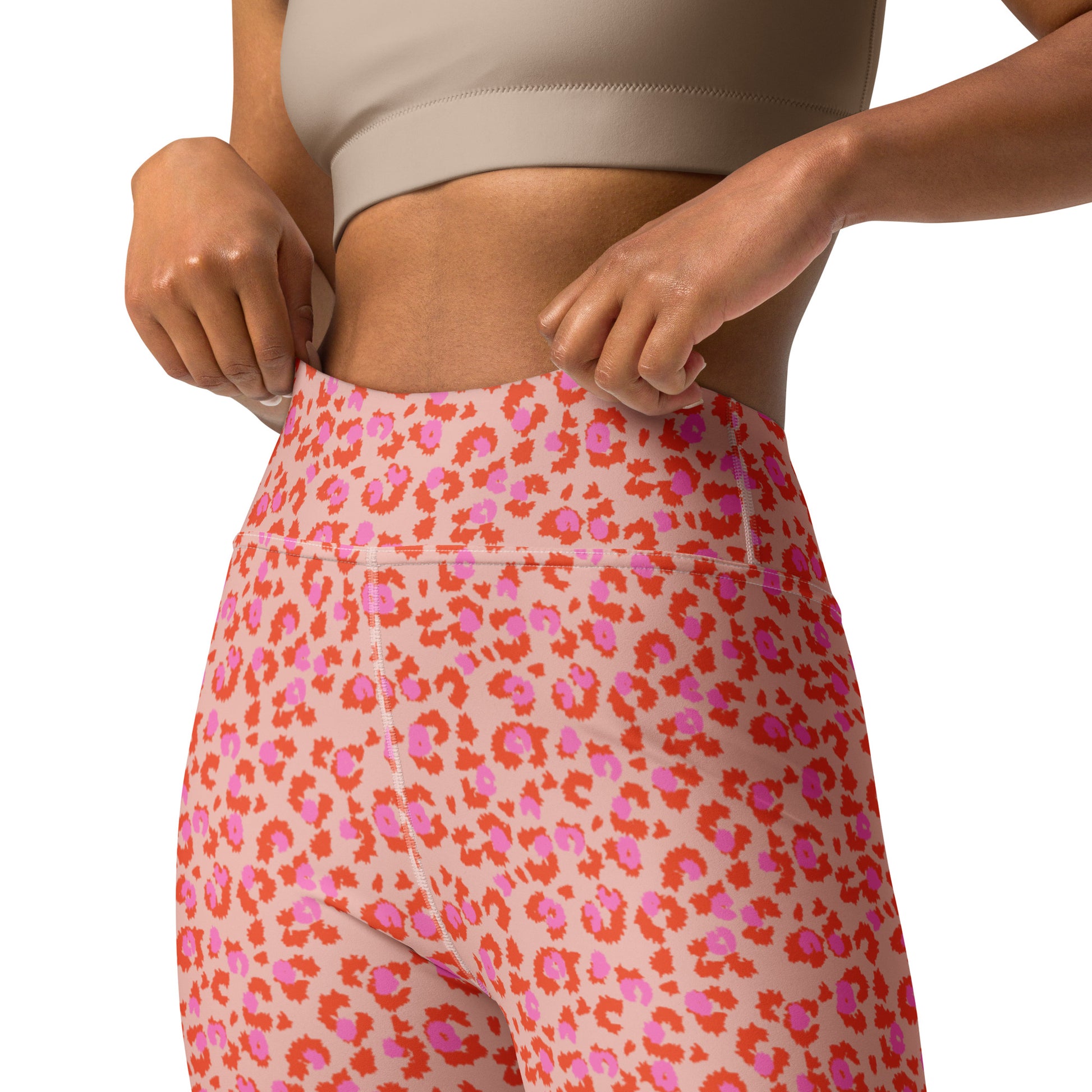 Close-up of a model wearing high-waisted leggings with a pink and orange floral pattern, paired with a beige sports bra against a white background. Pretty Chic Pink Leopard Print Yoga Pants for Workouts Activewear