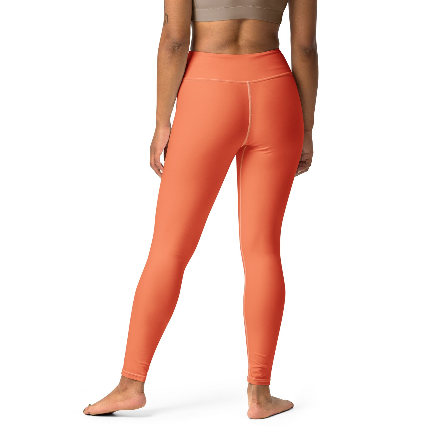 A model shown from the back wearing high-waisted, form-fitting leggings in a solid orange color, standing against a plain white background. Stylish Chic Comfortable Yoga Pants in Solid Coral Shade for Activewear