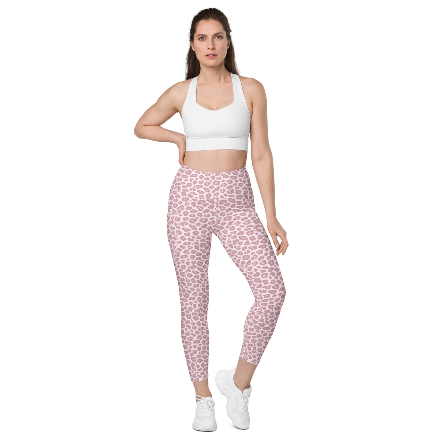A woman modeling pink leopard-print leggings with a white sports bra and white sneakers against a plain white background. Stylish Pink Pastel Leopard Print Leggings with Pockets Activewear