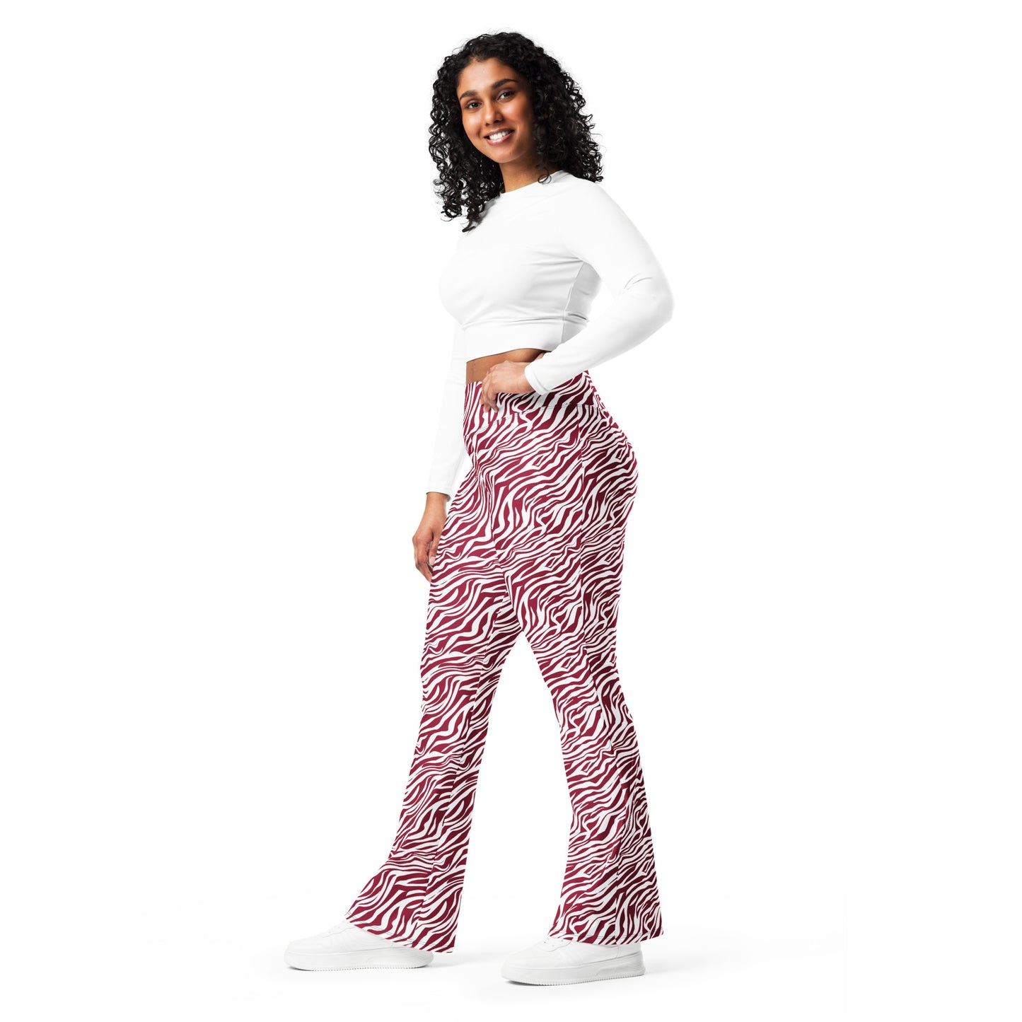A woman modeling high-waisted, wide-leg flare pants with a red and black zebra print, paired with a white long-sleeve crop top and white sneakers, against a solid white background. Trendy Comfortable Bold Red Zebra Print Flare Leggings Activewear