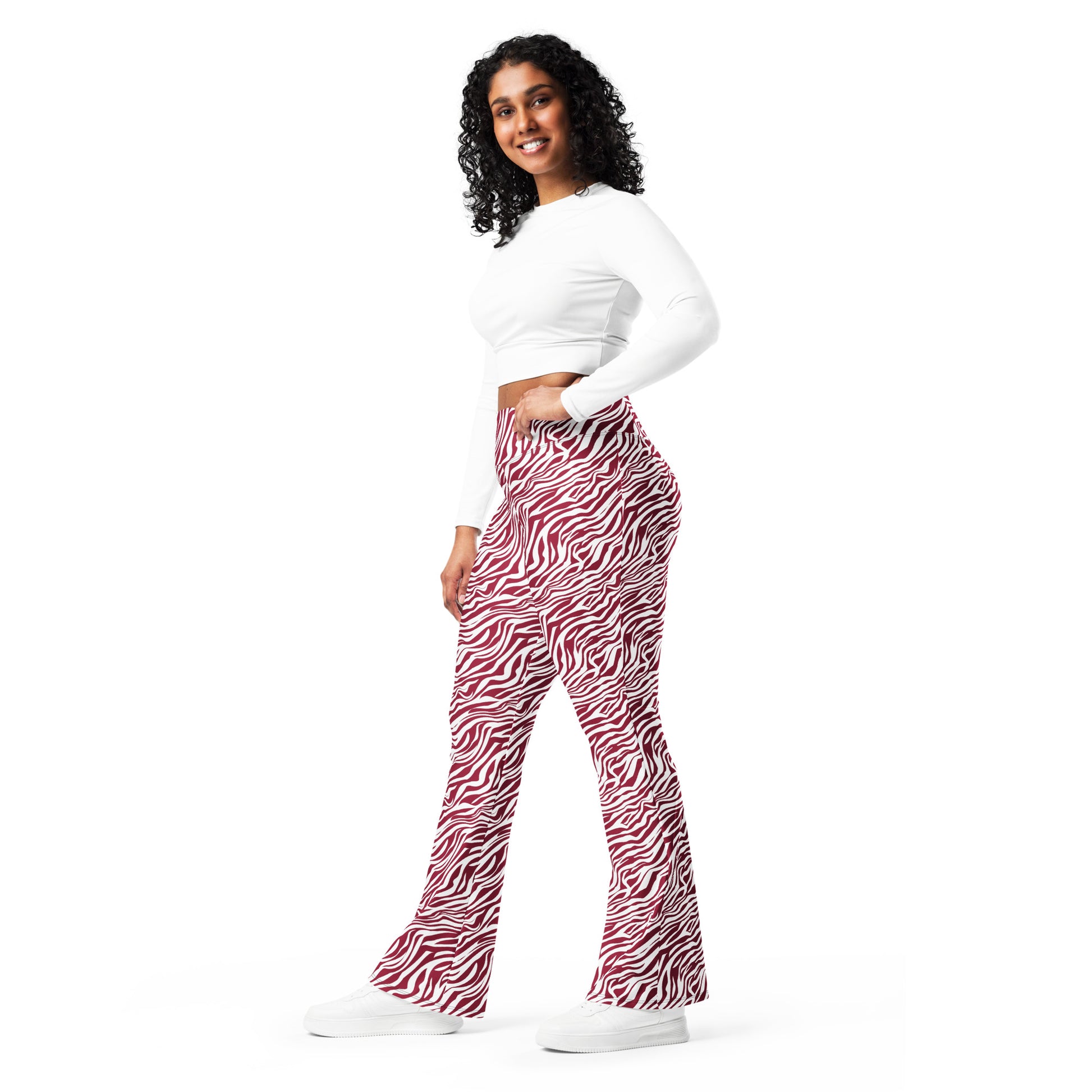 A woman modeling high-waisted, wide-leg flare pants with a red and black zebra print, paired with a white long-sleeve crop top and white sneakers, against a solid white background. Trendy Comfortable Bold Red Zebra Print Flare Leggings Activewear