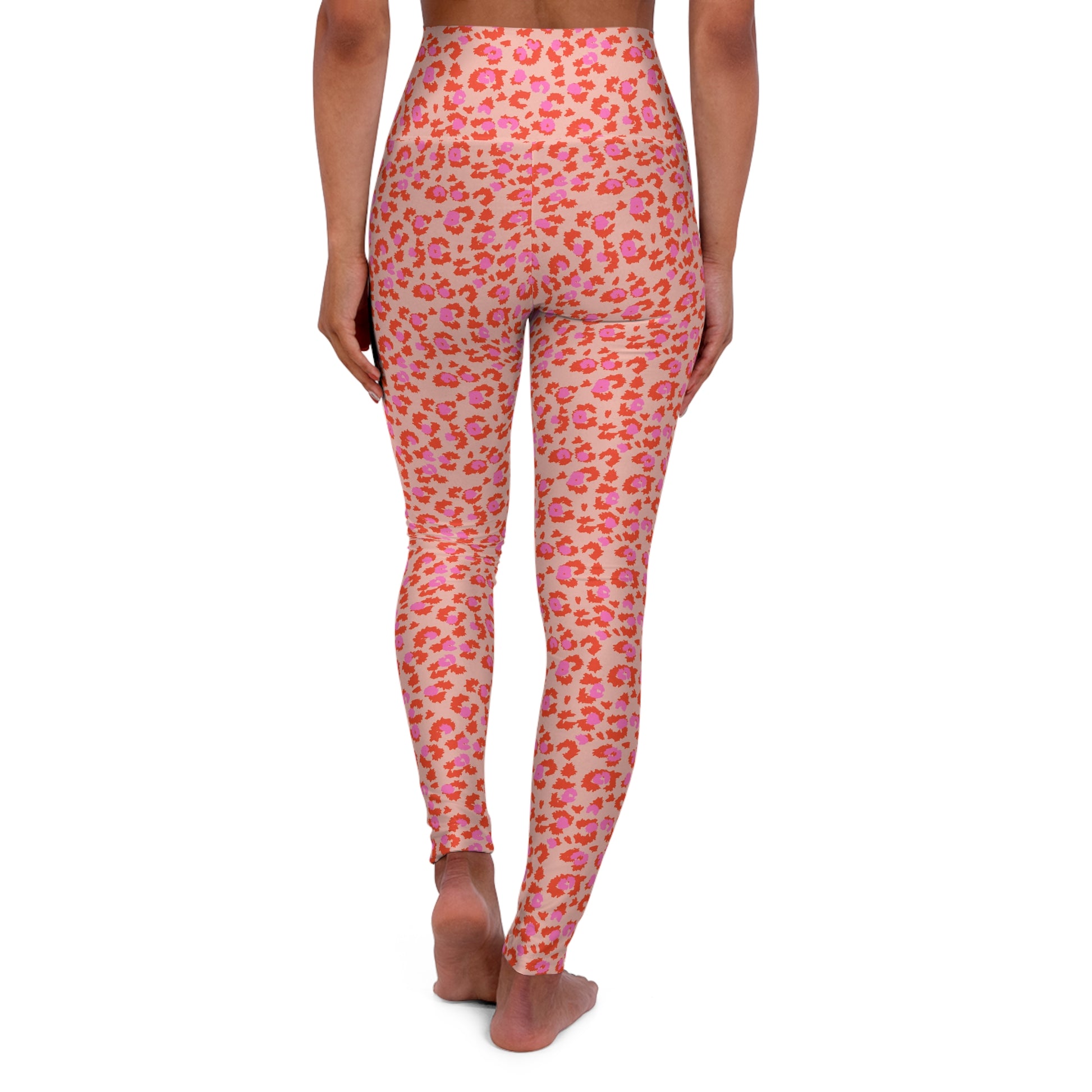 Rear view of a model wearing high-waisted leggings with a pink and orange leopard print pattern on a light peach background, set against a plain white studio background. Trendy Leopard Pattern Activewear for Workouts