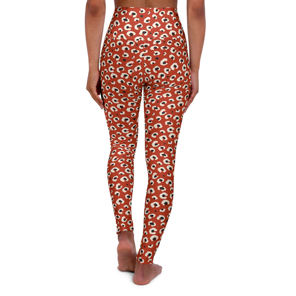 Rear view of a model wearing high-waisted leggings with an all-over repeating eye print on a rust-orange background, shown against a plain white studio background. Tropical Leopard Print High-Waisted Yoga Leggings Activewear