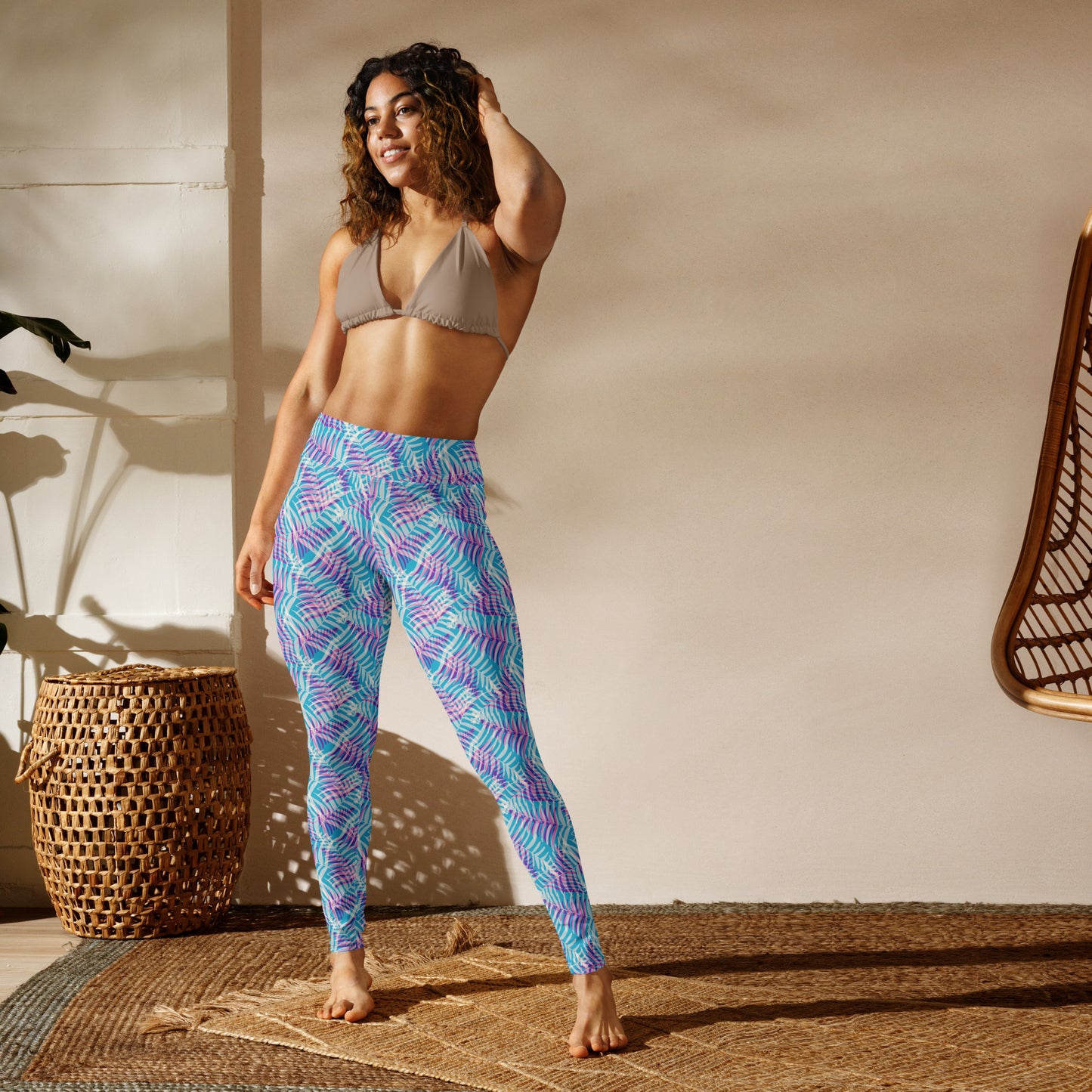 Woman wearing a beige bra and light blue leggings standing in a sunlit room with a woven basket and chair. Vibrant Bold Pastel Palm Print Activewear Yoga Leggings