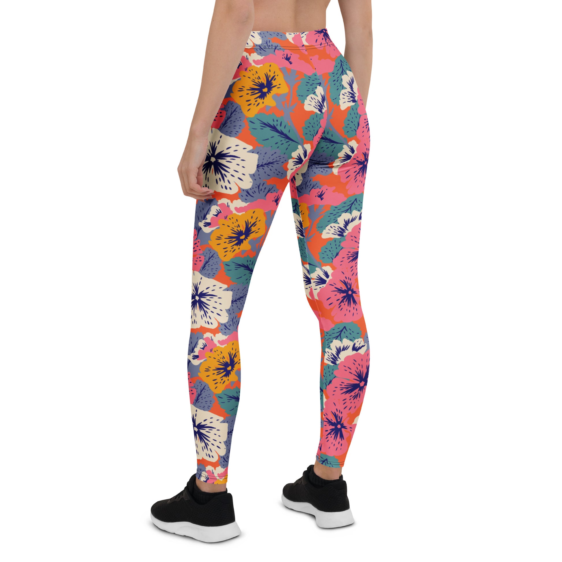 A person shown from the back wearing colorful floral leggings with black sneakers, photographed against a plain white studio background. Vibrant Floral Leggings with Abstract Tropical Designs