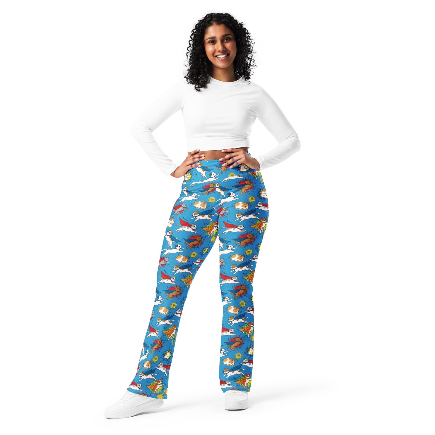 A woman modeling high-waisted flare pants with a colorful cartoon dragon pattern on a bright blue background, paired with a white long-sleeve crop top and white sneakers, against a plain white studio background. Whimsical Superhero Pets Printed Flare Leggings Activewear