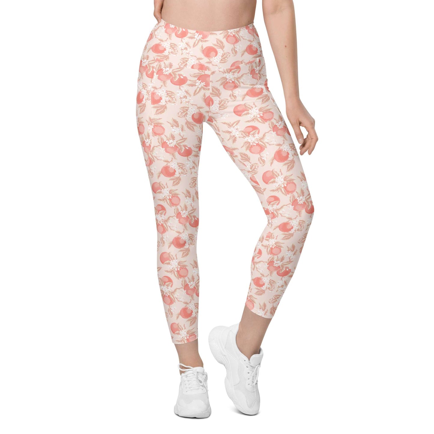 A model wearing high-waisted, ankle-length leggings with a peach and pink floral pattern on a cream background, paired with white sneakers, shown against a plain white background. Artistic Ditsy Floral Print Leggings with Pockets Activewear Artistic Stylized Ditsy Floral Pattern with Blue and Orange Botanical Motifs Leggings with Pockets Activewear Shop Artistic Ditsy Floral Print Leggings with Pockets, designed for bold outfits, flexible movement, and convenient everyday storage.