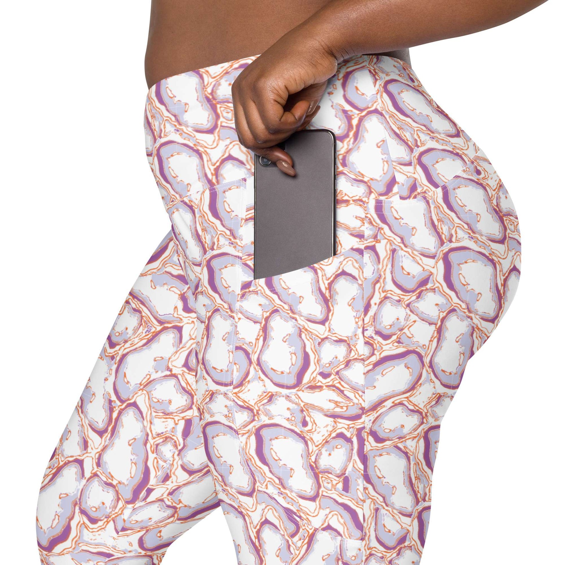 Close-up of a person wearing patterned leggings with a side pocket holding a dark gray smartphone. The leggings have an abstract geode or agate-like print in white, lavender, purple, and orange on a white background. Elegant Organic Marble Stone Leggings with Pockets Activewear Shop Elegant Organic Marble Stone Leggings with Pockets, designed for all-day comfort, flexible movement, and standout style. Elevate your activewear with Elegant Organic Marble Stone Leggings with Pockets, blending bold marble style