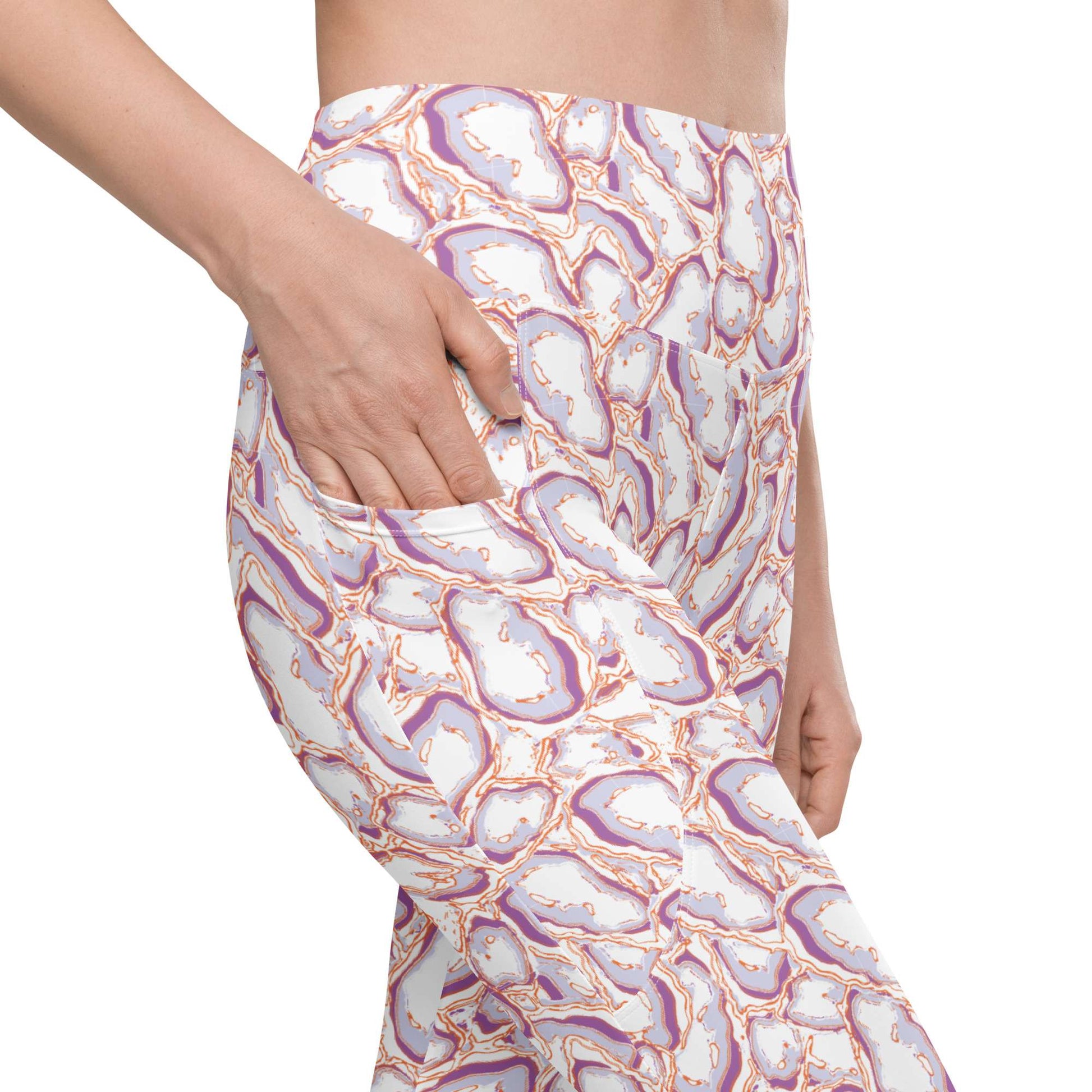 A close-up of a person wearing leggings with a white base and an abstract geode or agate-vein style print in purple, peach, and gray, shown from the waist down with one hand reaching into a side pocket. Elegant Organic Marble Stone Leggings with Pockets Activewear Shop Elegant Organic Marble Stone Leggings with Pockets, designed for all-day comfort, flexible movement, and standout style. Elevate your activewear with Elegant Organic Marble Stone Leggings with Pockets, blending bold marble style, comfort.