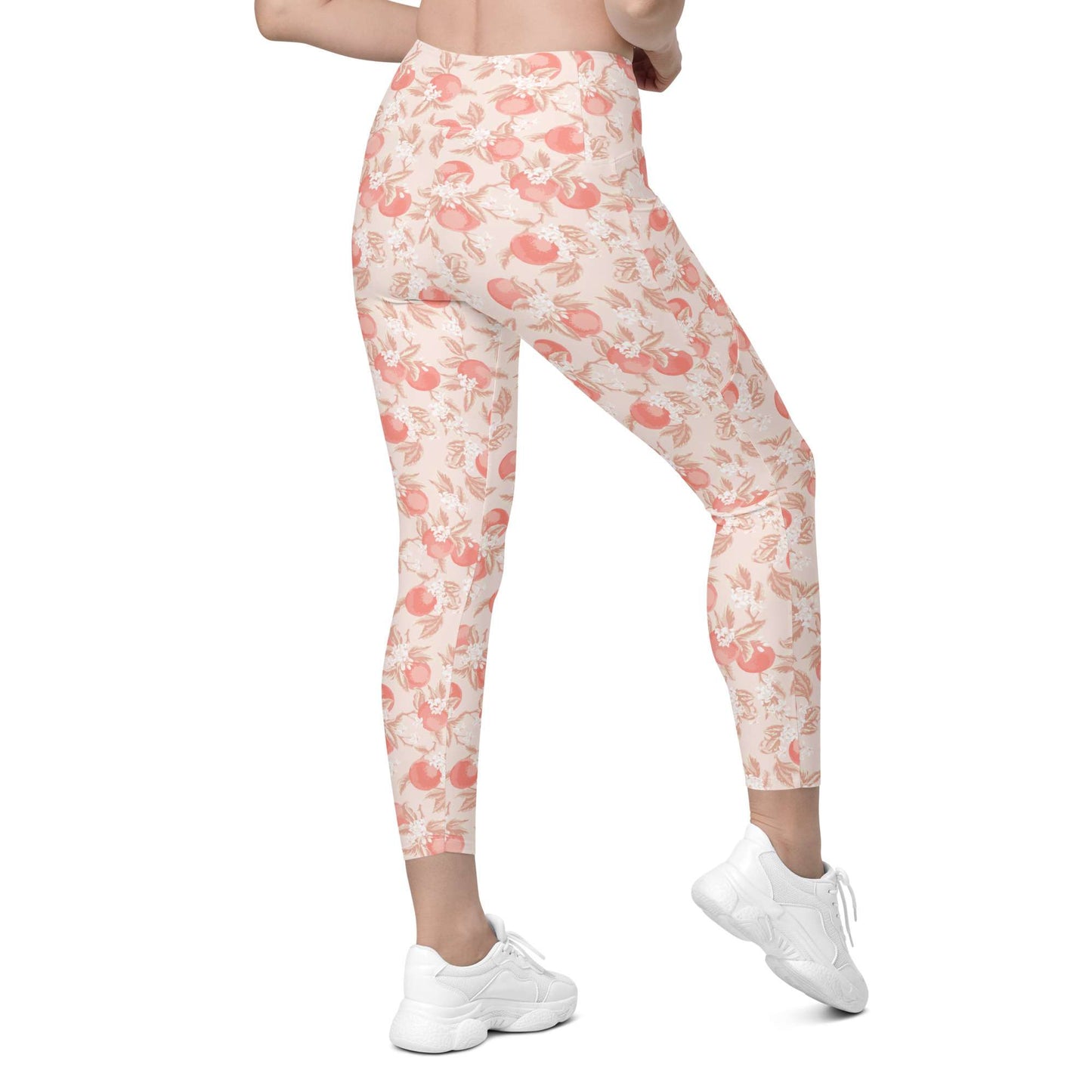 A person wearing high-waisted leggings with a peach and coral floral print on a cream background, paired with white sneakers, shown from the waist down against a plain white studio background. Artistic Ditsy Floral Print Leggings with Pockets Activewear Artistic Stylized Ditsy Floral Pattern with Blue and Orange Botanical Motifs Leggings with Pockets Activewear Shop Artistic Ditsy Floral Print Leggings with Pockets, designed for bold outfits, flexible movement, and convenient everyday storage.